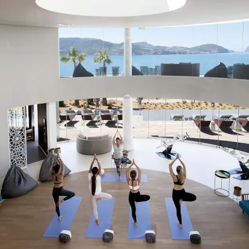 Group yoga session at 7Pines Resorts with a serene backdrop, epitomizing wellness and balance.