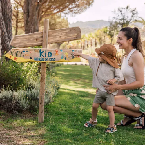 Child & woman pointing at House of Kids sign, enjoying 7Pines' family-friendly activities