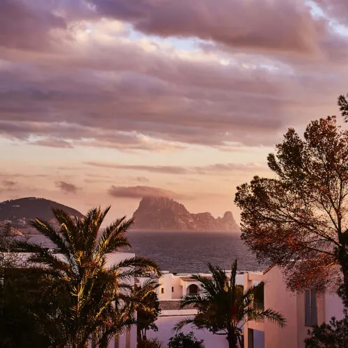 7Pines Resort Ibiza Sonnenuntergang mit Palmen und Blick auf Es Vedrà
