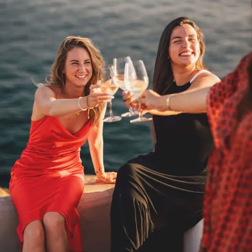 Women enjoying a bachelorette party outdoors with wine glasses at 7Pines Hotels & Resorts