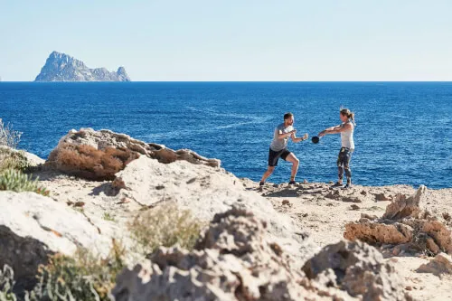 Couple on a rocky beach practicing wellness at 7Pines Resorts