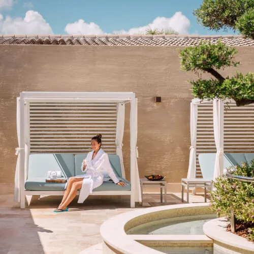 Woman relaxing on a lounge chair at 7Pines Hotels & Resorts, embodying summer vibes.